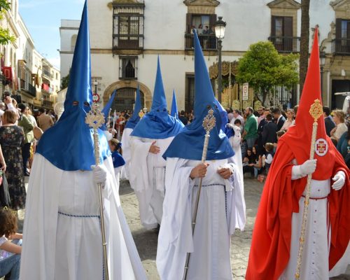 Colorful traditional procession with participants in robes and hoods in Seville, Spain.